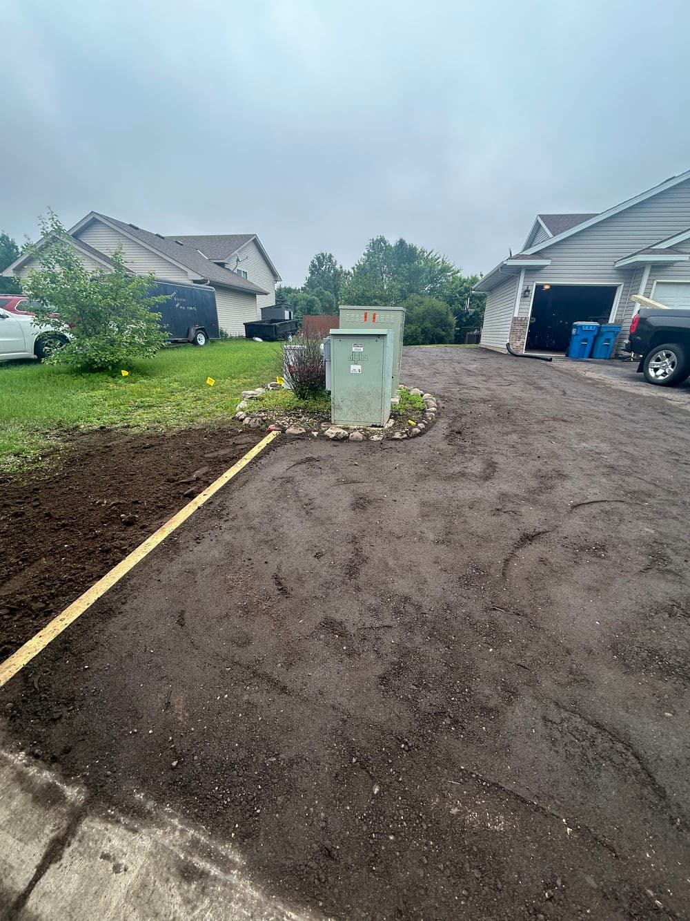 Utility box on a freshly graded driveway beside a house with landscaping features.