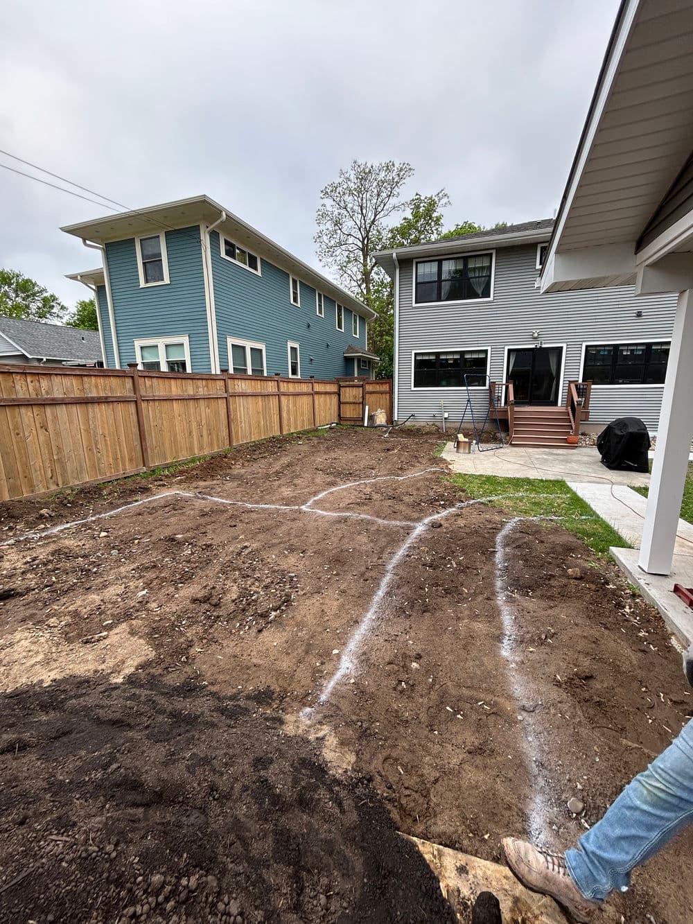 Residential backyard renovation with marked landscape layout and new utility lines.
