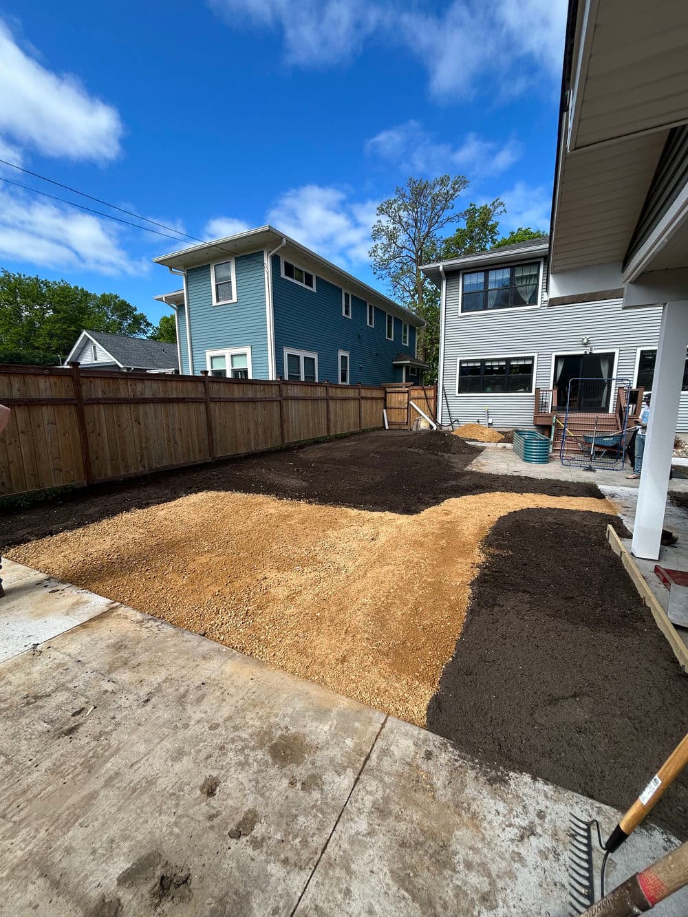 Home backyard landscaping project with gravel and soil preparation for gardening.
