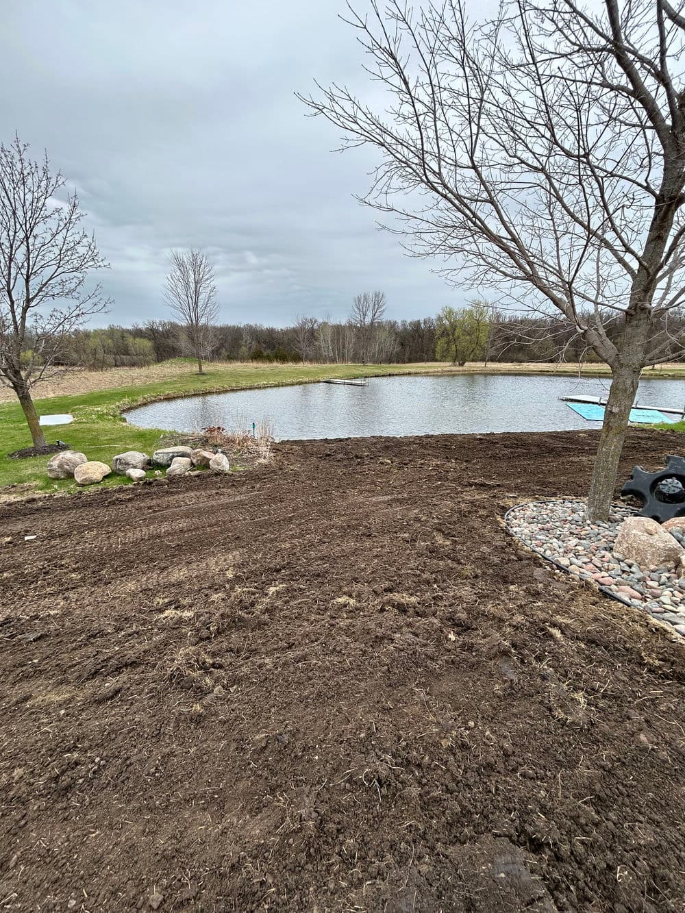 Cleared land with a pond and trees, ideal for landscaping or outdoor recreation.