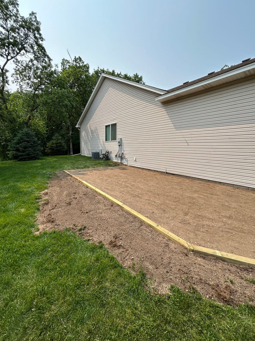 Backyard view of a house with a prepared garden area and grassy lawn.